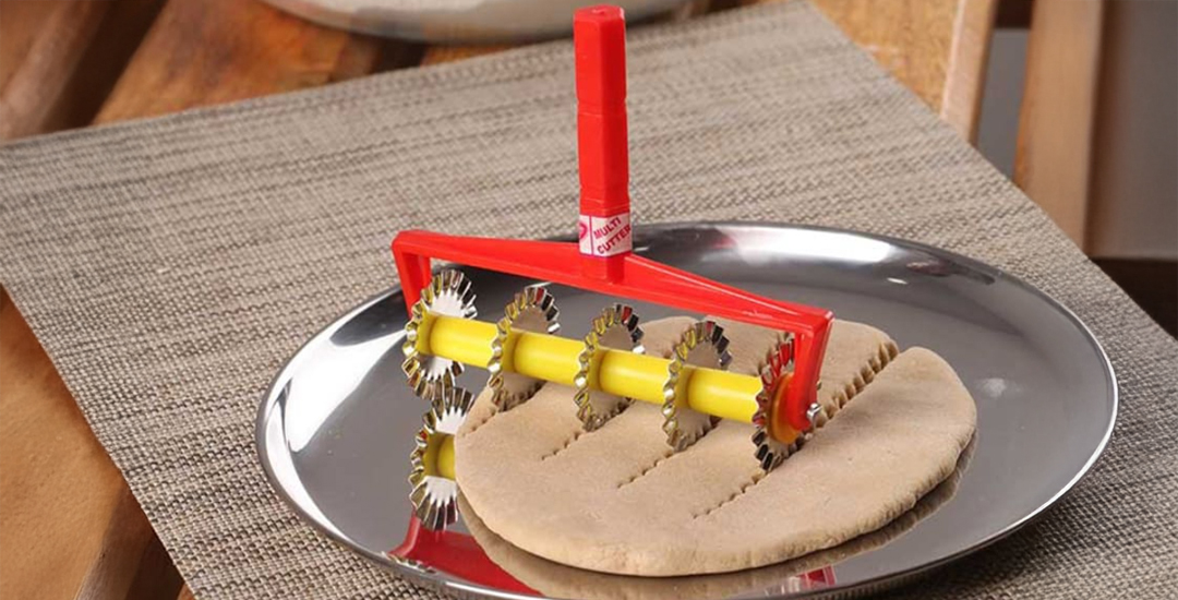 Stainless steel roller cutter with plastic handle for shaping mithai like kaju katli and shankarpali, designed for clean cuts and quick preparation.